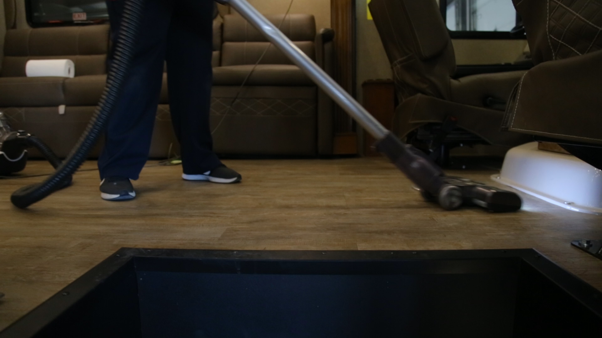A woman vacuums an RV floor.