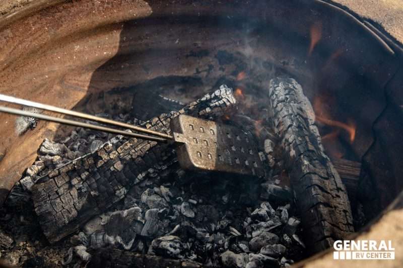 A pie iron cooks over a campfire.