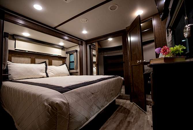 The king size bed and ample closet space of this RV bedroom are captured in a photograph.