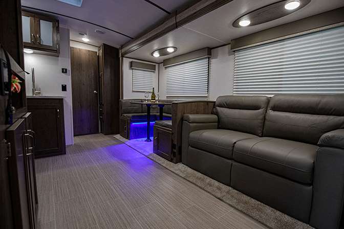 A view inside the Passport 3400QD living area shows the U-shaped dinette and leather couch across from the kitchen and entertainment center.