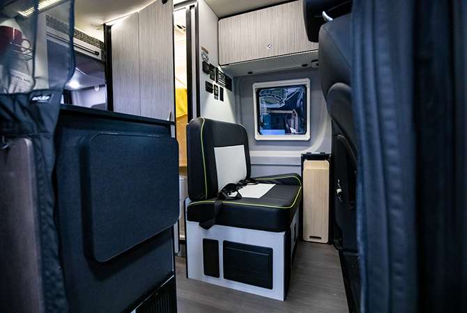 A photo of the mid-cabin section of the Winnebago Revel Class B motorhome / B-van shows a bench seat and flip-top counter extension that convert to a Flex Bed sleeping space.