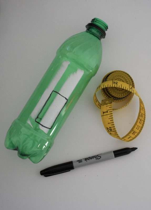 An overhead photo of a soda bottle with a measuring tape and Sharpie marker.