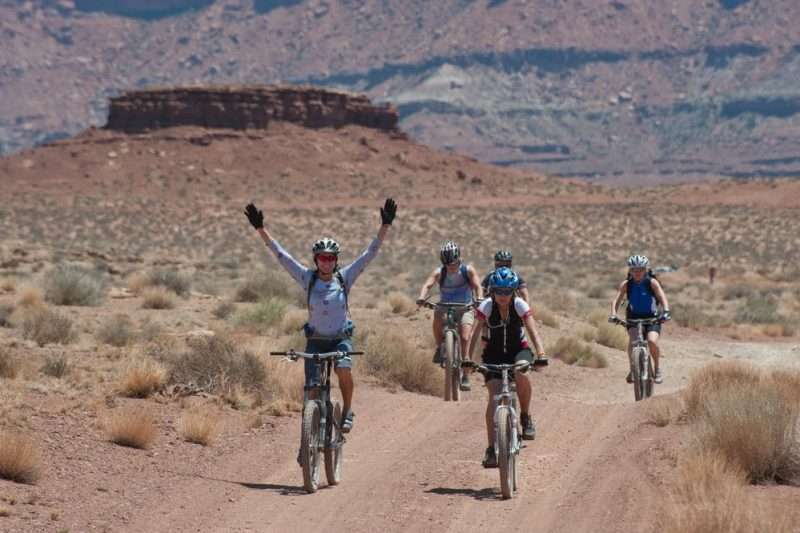 Five bicyclists on an unpaved road within Canyonlands National Park. 