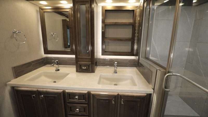 A photo of the Fleetwood Discovery LXE motorhome 40M floorplan master bathroom. This bathroom has a double sink vanity with generous storage and a large walk-in shower.