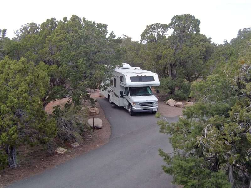 A Class C RV is parked on a campsite at Desert View Campground within Grand Canyon National Park. This site features paved road and campsite pad.