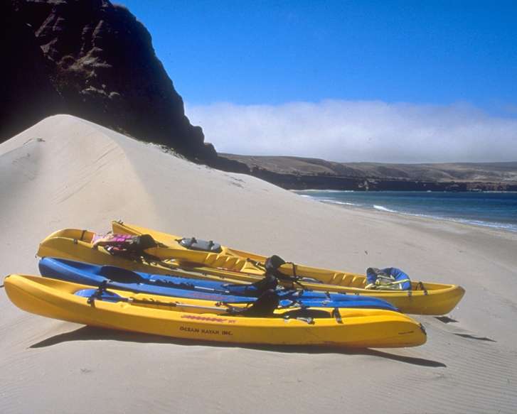 Bright yellow and blue kayaks sit on the sand at Water Canyon Beach.