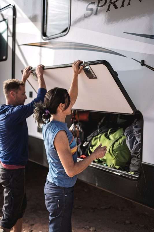 A man and woman pack an RV with gear.