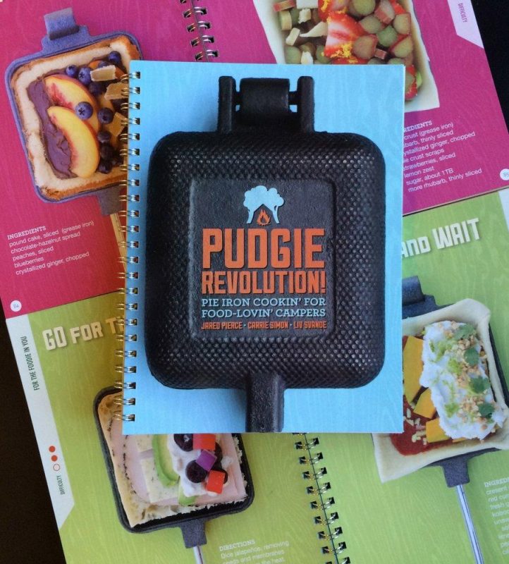 The colorful cover of the Pudgie Revolution Pie Iron cook book includes photos of various recipes and a cast iron pie iron that can make them all.