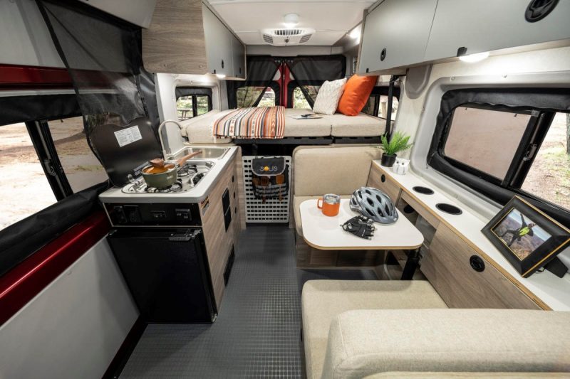 The interior of the Winnebago Solis Pocket has a dining/lounge area across from the galley and raised platform bed at the rear of the coach.