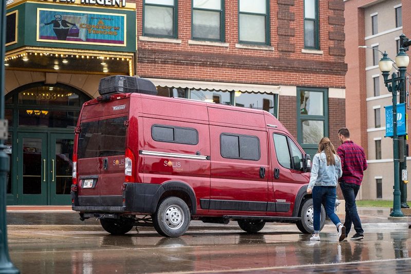 Couple walks to Solis Pocket parked on a city street outside of a theatre