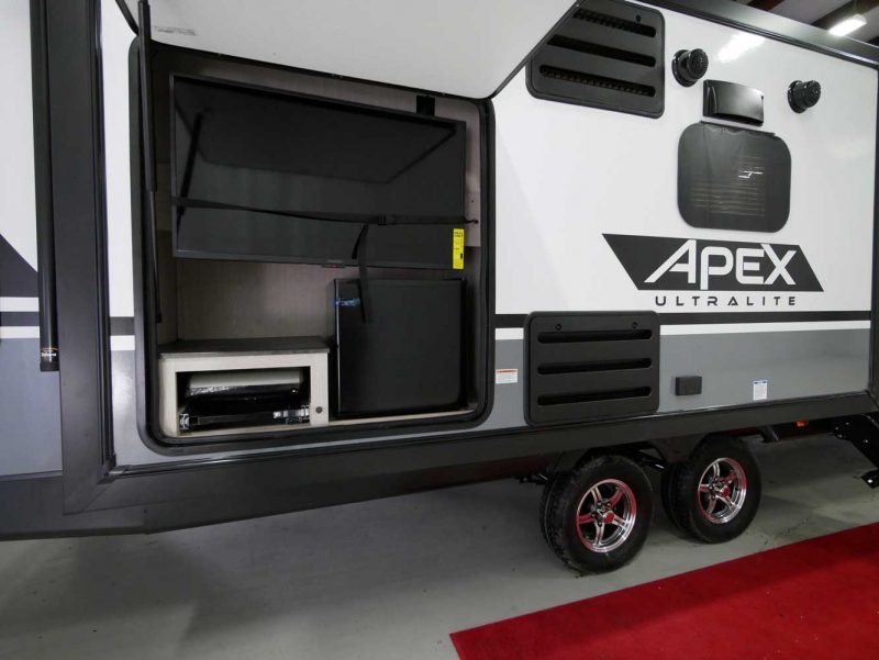 The Apex Ultra-Lite 293RLDS travel trailer from Coachmen RV is another RV with an outdoor kitchen. The 293RLDS floorplan features a large TV as well as an outdoor kitchen.