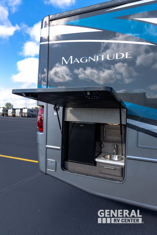 A closer look at the outdoor kitchen of the Magnitude RS36 by Thor Motor Coach shows the mini fridge and sink.