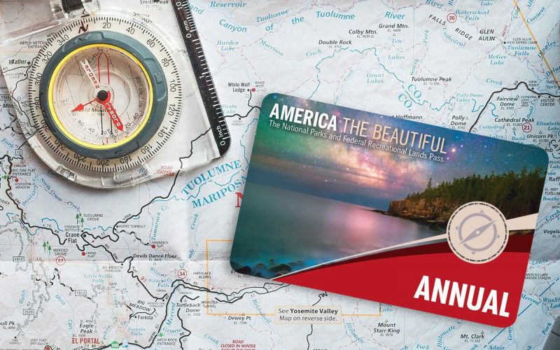 The National Park annual pass card laying on a map with a compass.