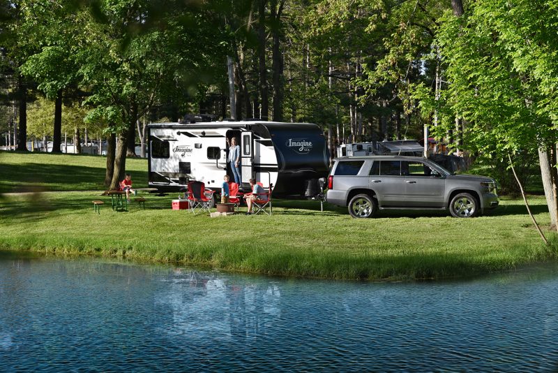 A family camping by the water in a travel trailer.