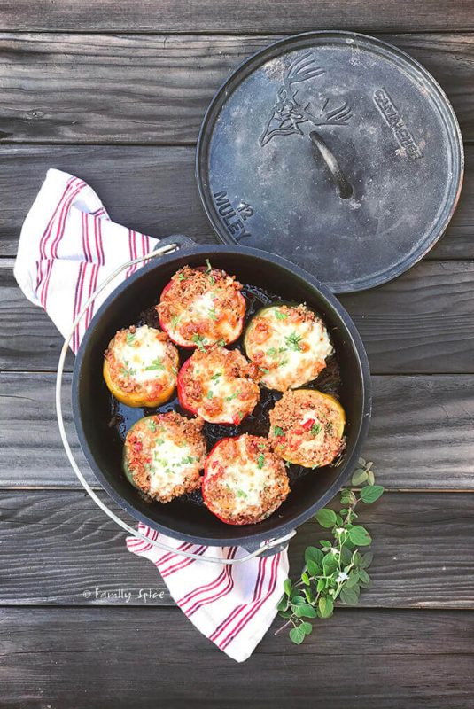 Freshly baked Campfire Dutch Oven Italian Stuffed Peppers sitting on a wood table.