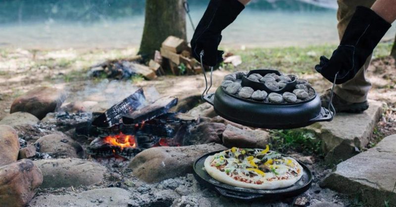 A man removing a freshly made Campfire Pizza.