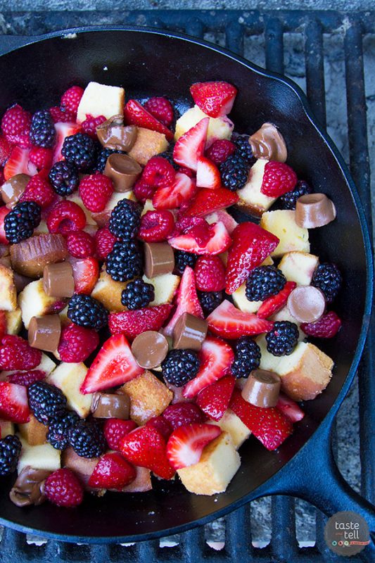A Pound Cake and Berry Campfire Skillet is over a campfire starting to be cooked.