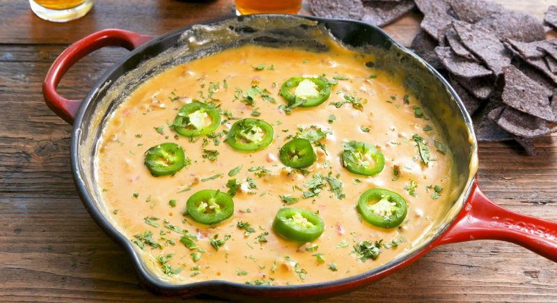 Campfire Queso ready to eat on a table with chips near it.