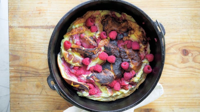 A freshly baked Campfire Raspberry Double Dutch Baby in a Dutch Oven.