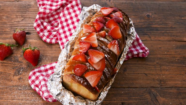 Freshly baked Campfire French Toast with strawberries and syrup on top.