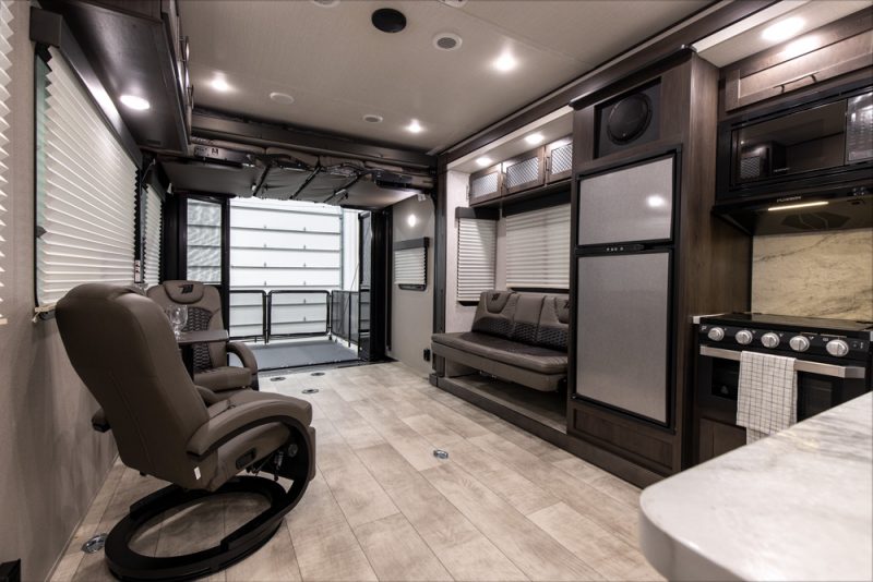 The photo is taken at the entry door looking into the RV, showcasing how spacious the floorplan of the kitchen and living room is.