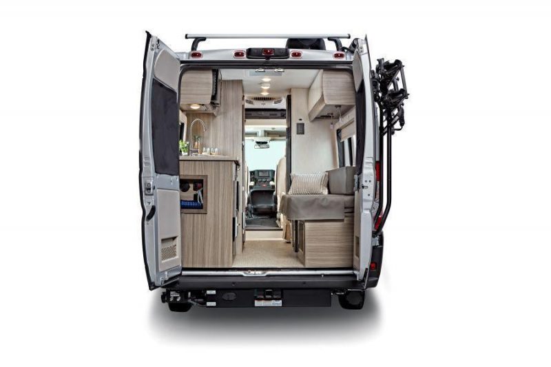 The rear doors of the Ethos camper van motorhome open to show the interior of the RV from rear to front. A convertible bench and galley kitchen are located towards the back of the coach.