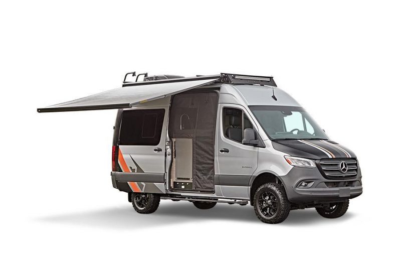An exterior shot of the Entegra Launch camper van shows it's awning extended and the side door screen.