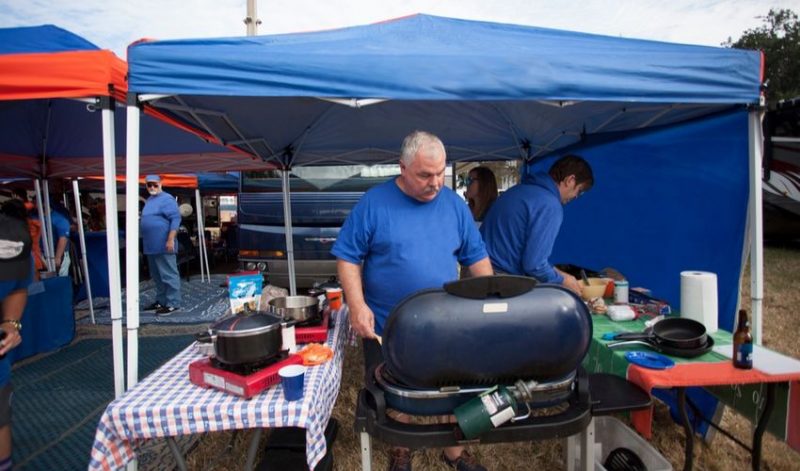 A man grilling under a pop up tent.