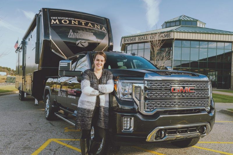 Cortni Armstrong of The Flipping Nomad standing next to her truck and fifth wheel that she renovated.